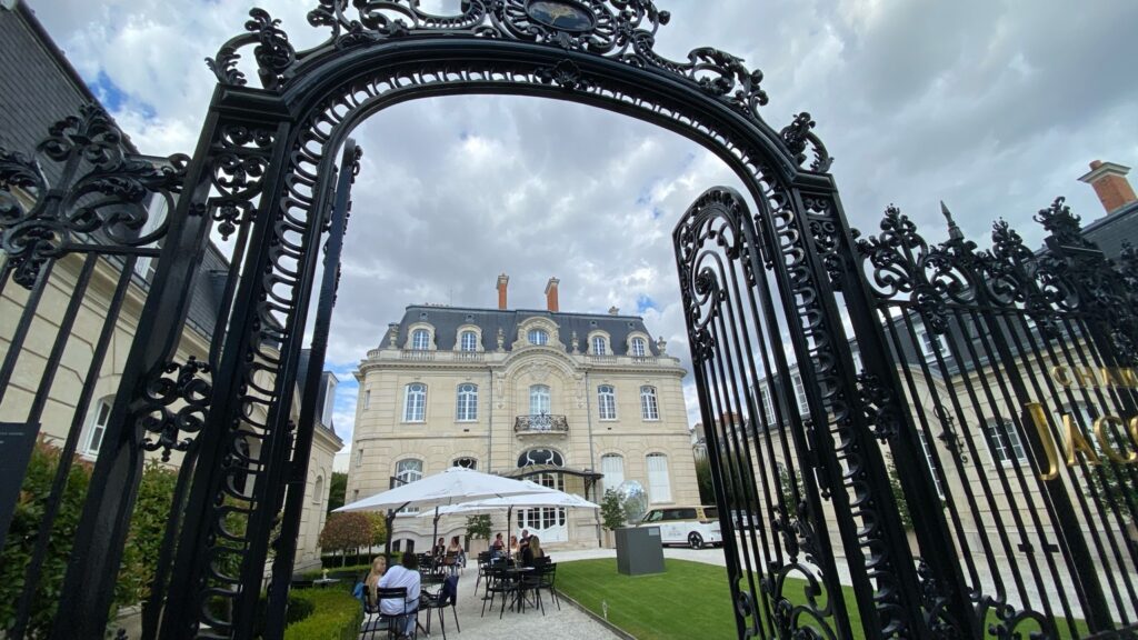 Terrace at a Champagne house in Reims framed by an ornate iron gate in summer